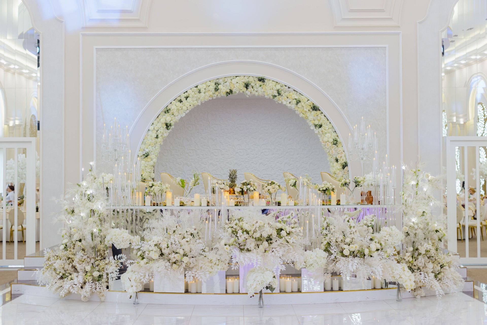Elegant wedding stage with white floral arrangements.